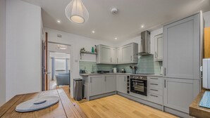 Una cucina moderna con mobili grigi, un tavolo da pranzo in legno e un forno incassato.