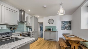 Una cucina moderna con piani in granito, elettrodomestici in acciaio inossidabile e un tavolo da pranzo in legno.