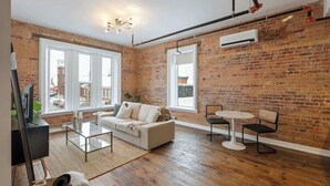 Un salon avec un mur en briques, un canapé, une table basse et un meuble pour la télévision.