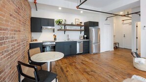 Une cuisine moderne avec un mur en briques, un plancher en bois et des appareils électroménagers en acier inoxydable.