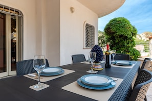 Une table à manger dressée avec des assiettes, des verres et une bouteille, entourée de chaises.