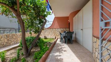 Une terrasse avec une table et des chaises, un arbre et un mur en pierre.