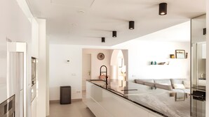 Una cocina moderna con encimera de vidrio, un lavamanos y horno empotrado.