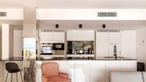 Una cocina moderna con armarios blancos, encimera negra y horno integrado.