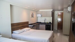Ein Hotelzimmer mit zwei Betten, einer Küchenzeile und einem Badezimmer.