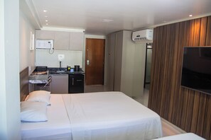 A hotel room with a bed, a desk with a microwave, a television, and a wardrobe. - Blue Sunset By Sun&Sea (João Pessoa)