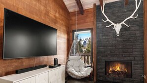 Ein modernes Wohnzimmer mit Fernseher, Hängekorbsessel, Kamin und Steinwand.