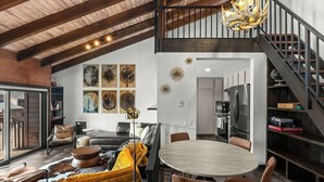 Ein geräumiger Wohnbereich mit hohen Decken, einem Esstisch und einer Treppe, die in eine obere Etage führt.