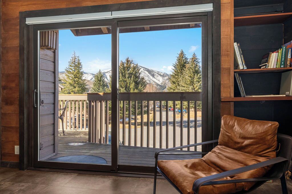 A room with a sliding glass door leading to a deck with a mountain view.