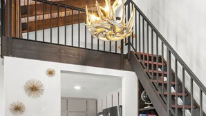 Ein Essbereich mit rundem Tisch und Stühlen, einer Treppe und einer Küche im Hintergrund.