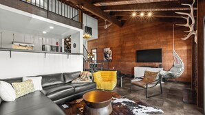 Ein modernes Wohnzimmer mit einem schwarzen Ledersofa, einem runden Couchtisch und einem Hängesessel.