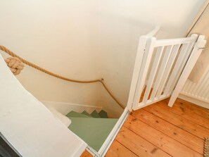 A white staircase with a green step, a white railing, and a rope on the wall. - Vintner's Cottage (Norwich)