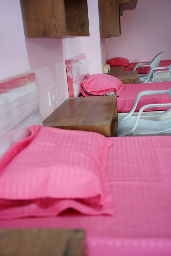 A room with bunk beds, a wooden table, and a pink bedspread.