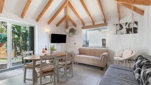 A spacious room with a wooden ceiling, a dining table with chairs, a sofa, a hanging chair, and a TV mounted on the wall. - Vacation Home 'Casa Dell Anna' with Sea View, Wi-Fi and Air Conditioning (Icod de los Vinos)
