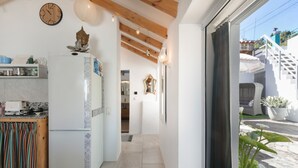 A kitchen with a refrigerator, a clock, and a window with a view of a staircase and plants outside. - Vacation Home 'Casa Dell Anna' with Sea View, Wi-Fi and Air Conditioning (Icod de los Vinos)