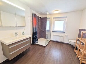 Een douche, handdoeken, zeep, toiletpapier