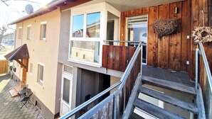 Een meerlaags gebouw met een houten gevel, een balkon en een trap naar de bovenverdieping.
