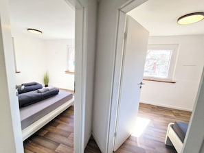 Ein modernes Zimmer mit eingebauter Sitzbank, einer Tür zu einem weiteren Raum und einem Fenster mit Blick.