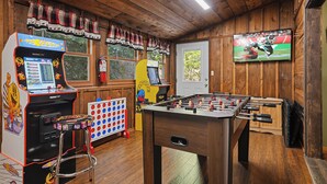 A wooden-floored room with a foosball table, a television, and two arcade machines. - Cozy* Secluded*Firepit*Hot Tub*Seeps 7 (Pigeon Forge)