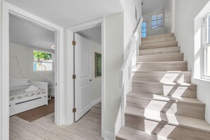 A staircase leading to a second floor, a bedroom with a bed and a window, and a door leading to another room. - Sunny Palms (Treasure Island)