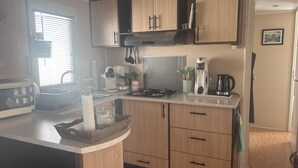 Una cucina compatta con mobili in legno, un fornello a gas, una macchina da caffè e un lavello.