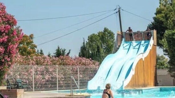Una piscina con uno scivolo acquatico e una persona in piedi accanto.