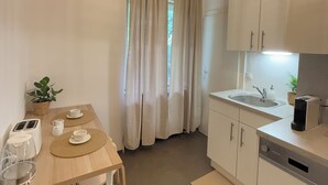 A compact kitchen with a dining area, a toaster, a kettle, and a sink. - Stylish apartment in the city center (Graz)