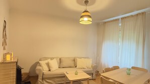 A living room with a sofa, a dining table, and a hanging light fixture. - Stylish apartment in the city center (Graz)