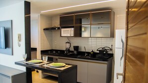 Une cuisine moderne avec un plan de travail noir, des armoires blanches et un four à micro-ondes encastré.