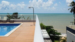 Un espace piscine avec vue sur l’océan, une clôture blanche et un lampadaire en métal.