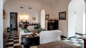 A spacious living room with a checkered floor, a fireplace, and a view through an archway. - Villa Margi · Pool · Sea View (Vico Equense)