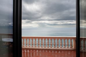 A balcony with a railing, a view of the sea, and a cloudy sky.