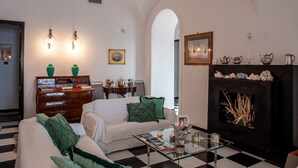 A living room with a fireplace, a sofa, a coffee table, and a bookshelf. - Villa Margi · Pool · Sea View (Vico Equense)