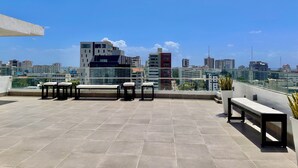 Une terrasse sur le toit, dotée d’un sol carrelé, d’un banc et d’une table.