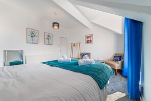 Une chambre à coucher avec un lit, une chaise, un bureau et une fenêtre avec des rideaux.