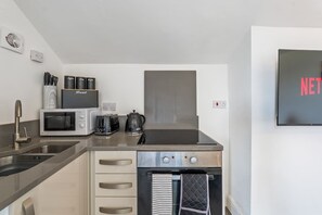 Une cuisine moderne équipée d’un four à micro-ondes, d’une machine à café, d’une bouilloire et d’un four encastré.