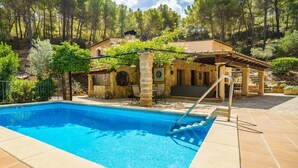 A swimming pool with a stone structure and a pergola. - Holiday Home 'Can Miquel De Sa Teia' with Mountain View, Private Pool and Wi-Fi (Illes Balears)