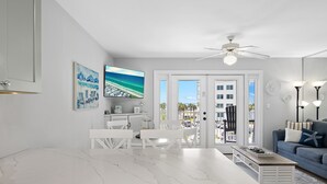 Een moderne woonkamer met een witte marmeren tafel, een blauwe bank en een plafondventilator.