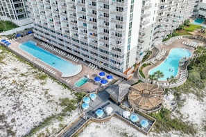 A high-rise hotel with multiple balconies, a central swimming pool, and a separate pool area. - 🌅Stunning Gulf Front Views | 3 Pools | Pelican Beach 1912🌅 (Destin)