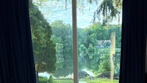 A bedroom with a large bed, a view of a lake, and curtains. - Spacious Lake Retreat, Stunning Sunset Views, Private Outdoor Entertaining. (Green Township)