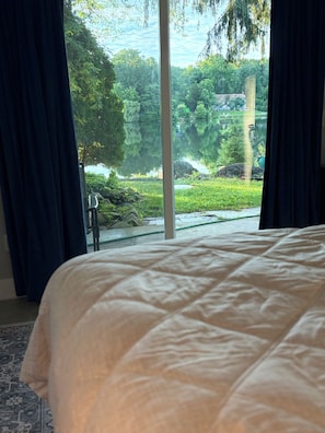 Une chambre avec un grand lit, une vue sur un lac et des rideaux.