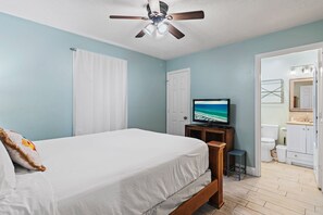 A bedroom with a bed, a ceiling fan, a television, and a bathroom visible through an open door. - 🌴Private Beach Path | Pool | St. Martin Beachwalk Villas 313☀️ (Destin)