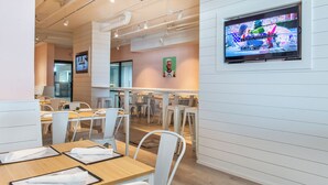 A modern restaurant interior with white furniture, a flat-screen TV on the wall, and a wooden floor. - 🌅Gulf Front Views | Resort Pool | SunDestin 205🌅 (Destin)