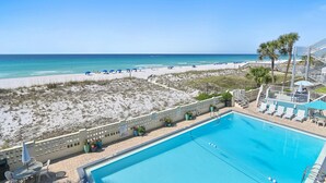 A pool with a view of the beach and ocean, a fenced area with potted plants, and a staircase leading to a deck. - 🏖️Gulf Front 3rd Floor | Pool & Beach View | Aqua Villa 302🏖️ (Fort Walton Beach)