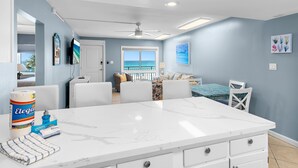 A room with a large white marble table, a ceiling fan, and a view of the ocean. - 🏖️Gulf Front 3rd Floor | Pool & Beach View | Aqua Villa 302🏖️ (Fort Walton Beach)