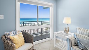 A balcony with a view of the ocean, wicker furniture, a white table, and a lamp. - 🏖️Gulf Front 3rd Floor | Pool & Beach View | Aqua Villa 302🏖️ (Fort Walton Beach)