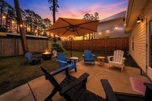 An outdoor patio with Adirondack chairs, a fire pit, and string lights. - 🏖️4 Bikes | Walk to Beach | Pet Friendly | Prime Location | Mermaid Manor🏖️ (Panama City Beach)