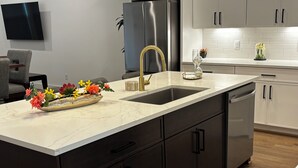 Una cucina moderna con un piano di lavoro in marmo, elettrodomestici in acciaio inossidabile e mobili scuri.