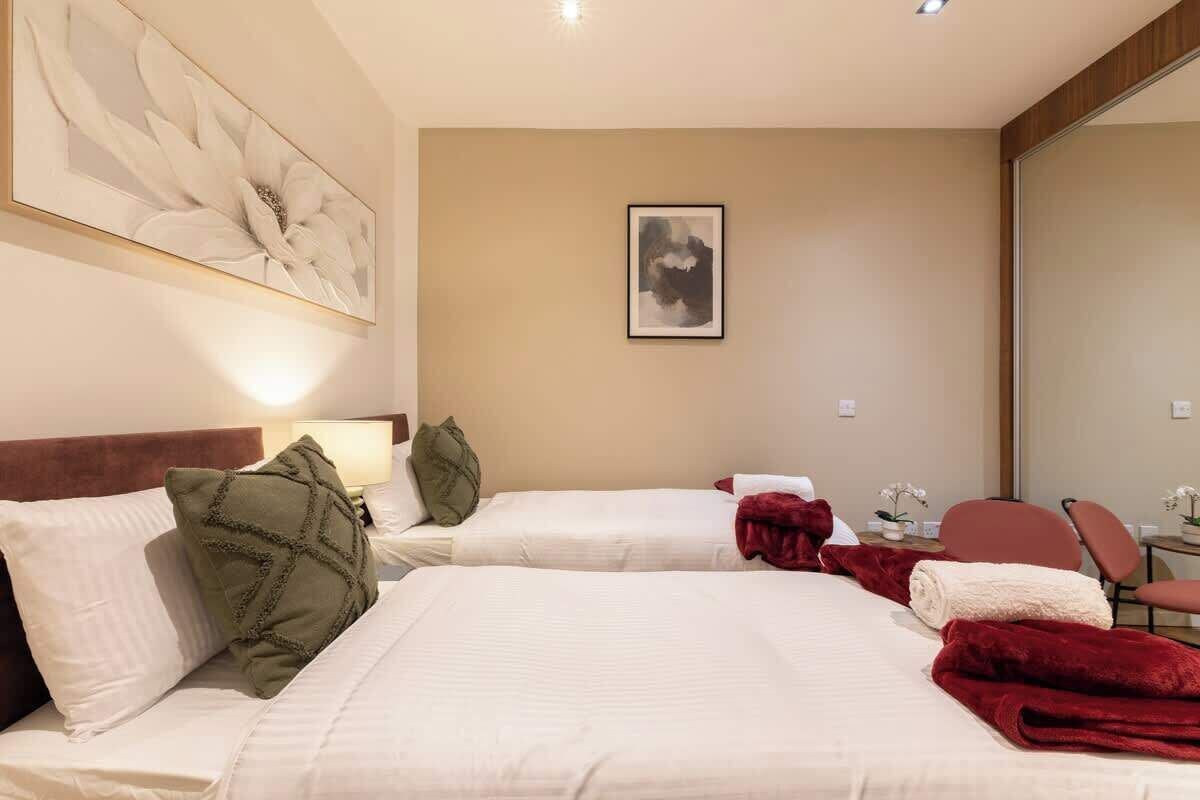A hotel room with two beds, a large abstract painting, a framed picture on the wall, and a desk with a chair.