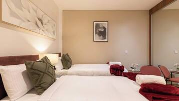 A hotel room with two beds, a large abstract painting, a framed picture on the wall, and a desk with a chair.